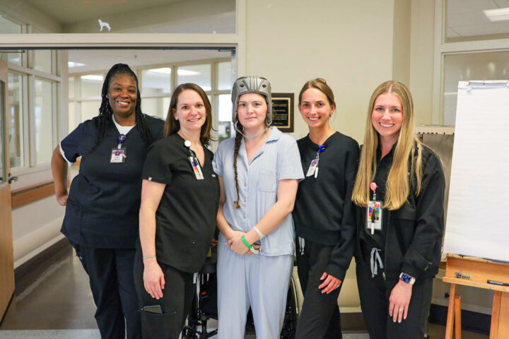 Patient stands to pose with multiple of her therapists