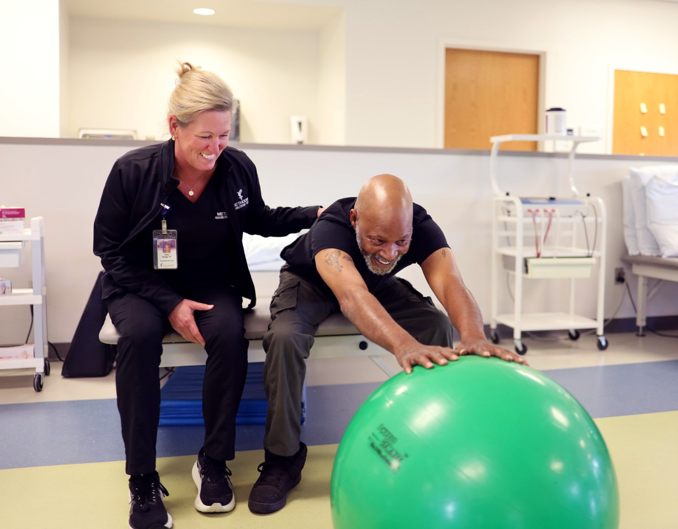 Outpatient therapy with patient stretching with an exercise ball with the support of a therapist