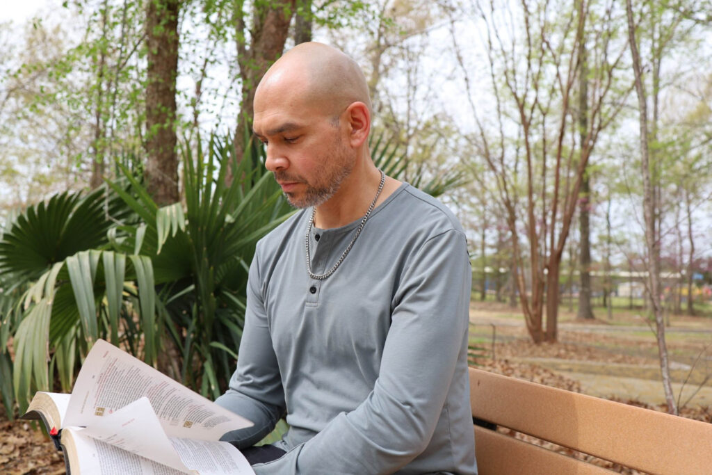 Christopher Johnsen reading a bible while sitting on a park bench