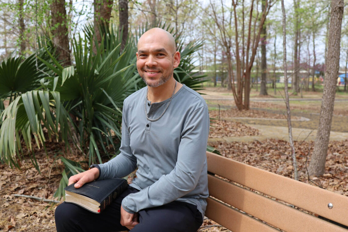 Christopher Johnsen reading a bible while sitting on a park bench