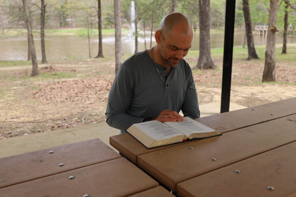 Christopher Johnsen reading a bible at a park
