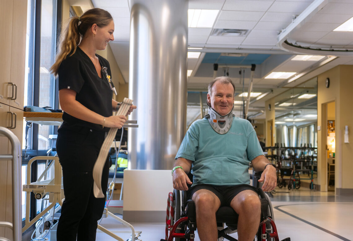 Patient and therapist. The patient is wearing a neck brace and is seated in a wheel chair
