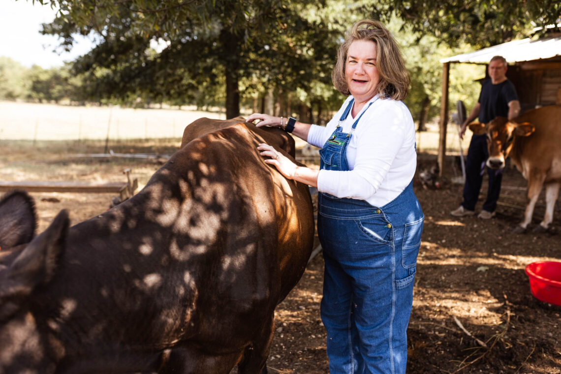Amy Degrado poses next to one of her cows on the farm