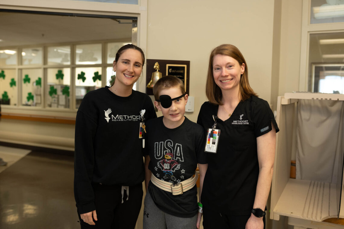 Child patient with two therapists posing for a photo
